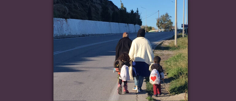 Eine Mutter geht mit ihren zwei Kindern am Straßenrand einer Straße auf Lesbos entlang. Sie sind Geflüchtete