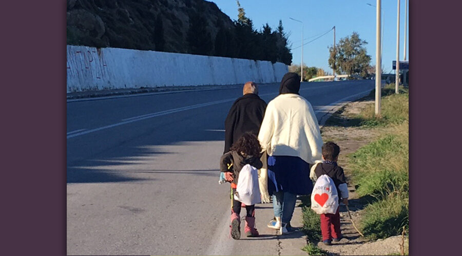 Eine Mutter geht mit ihren zwei Kindern am Straßenrand einer Straße auf Lesbos entlang. Sie sind Geflüchtete