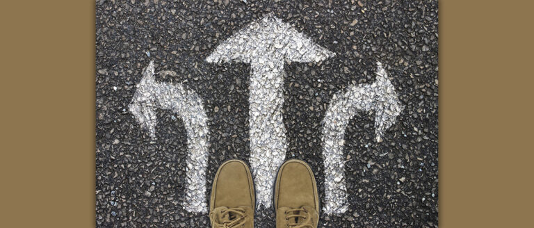 auf dem Boden sind drei weiße Kreide-Pfeile, die geradeaus, nach rechts und nach links zeigen. Die Schuhe, die zu sehen sind, suggerieren, dass es um eine Wahl geht.