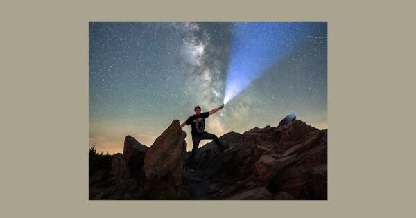 Prof. S. Seiffert steht nachts auf den Felsen der Wolfswarte im Oberharz und leuchtet mit einer starken Taschenlampe in den Himmel. Das Bild trägt den Titel: Hoffnung?