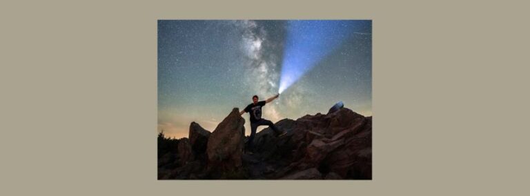 Prof. S. Seiffert steht nachts auf den Felsen der Wolfswarte im Oberharz und leuchtet mit einer starken Taschenlampe in den Himmel. Das Bild trägt den Titel: Hoffnung?