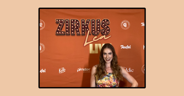 Die Artistin Lea Toran Jenner steht vor einer Wand, die ihre eigene Show Zirkus Lea Live promotet